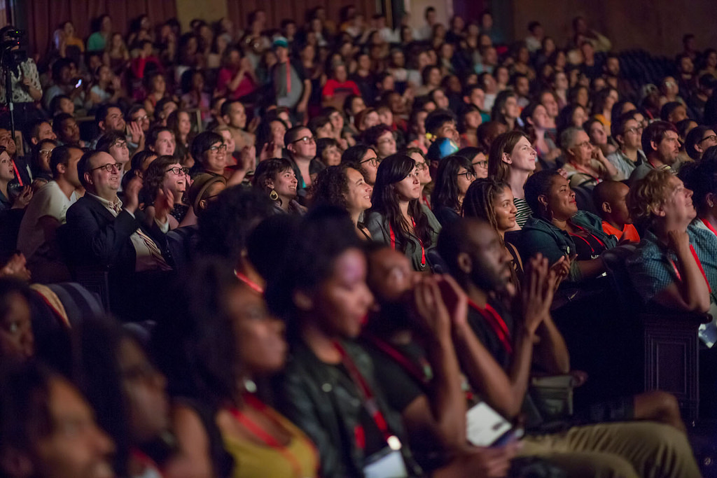 Audience in a dark auditorium looking at the stage