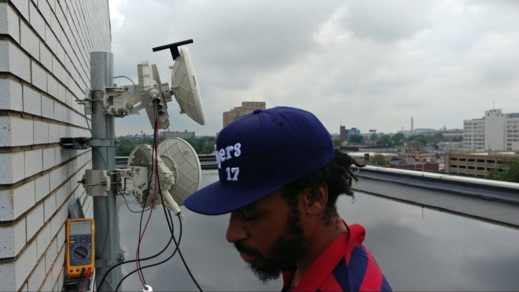 EII member on top of a commercial roof testing a mesh network satellite installation