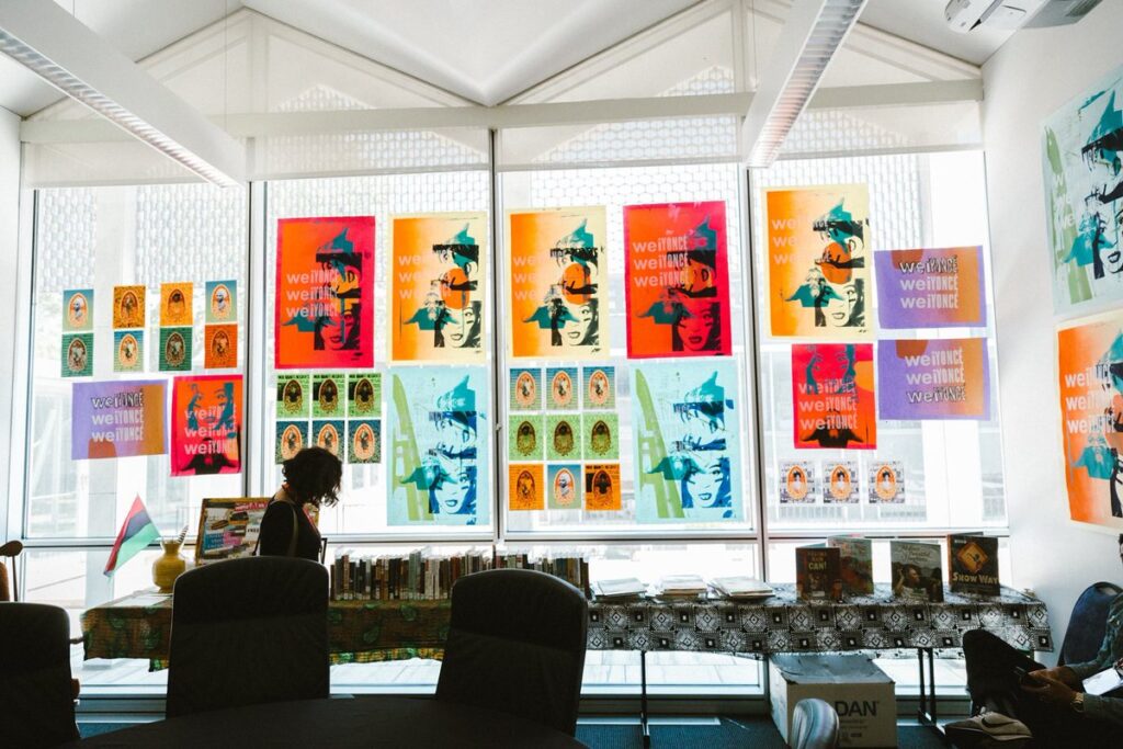 A row of folding tables with books for sale, and a backdrop of a wall of poster art