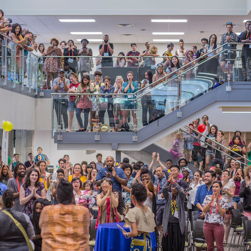 A large crowd gathered indoors at the AMC on two floors and on the stairs cheering and clapping