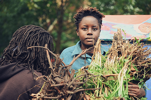 Still from the Sidelots of people holding harvested vegetables
