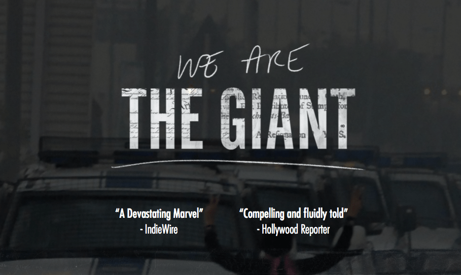 Movie poster for "We Are The Giant" with a very muted image of a line of cop cars and a person with their back to the viewer with their arms up and their hand showing peace signs